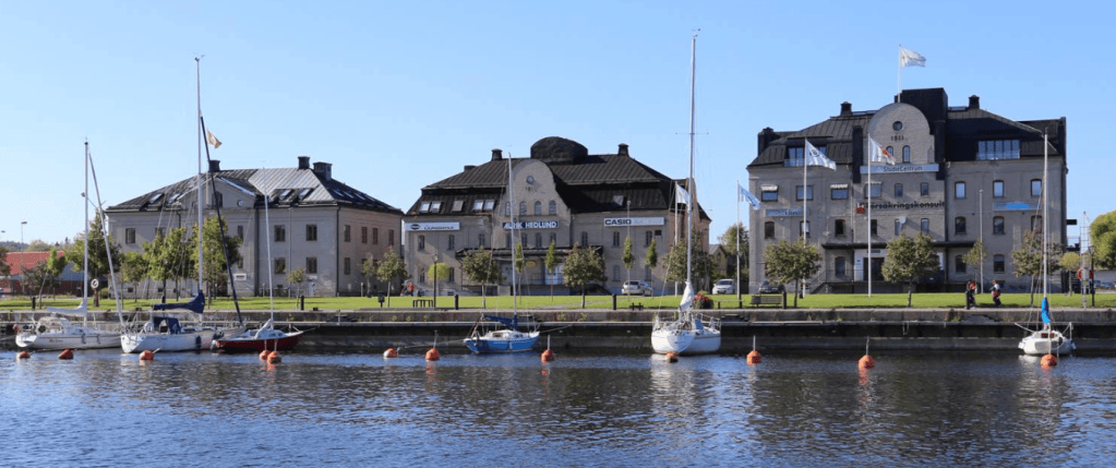 Utsikt över en hamn med segelbåtar och byggnader i bakgrunden.